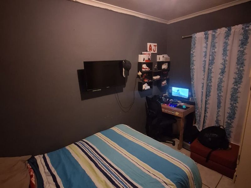 A functional bedroom featuring tiled flooring and dark-painted walls, providing a versatile space for rest or study.