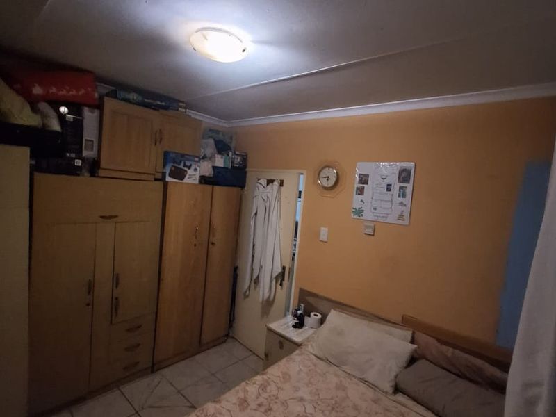 A functional bedroom featuring built-in wooden cupboards and tiled flooring, providing a practical layout for sleeping quarters.