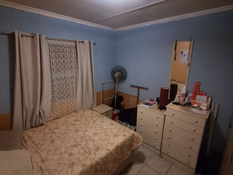 A bedroom featuring tiled flooring and a central ceiling light fixture, providing a functional space ready for cosmetic updates.