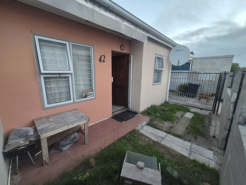 Exterior view of the front entrance featuring a tiled porch area, security gates, and satellite dish installation.