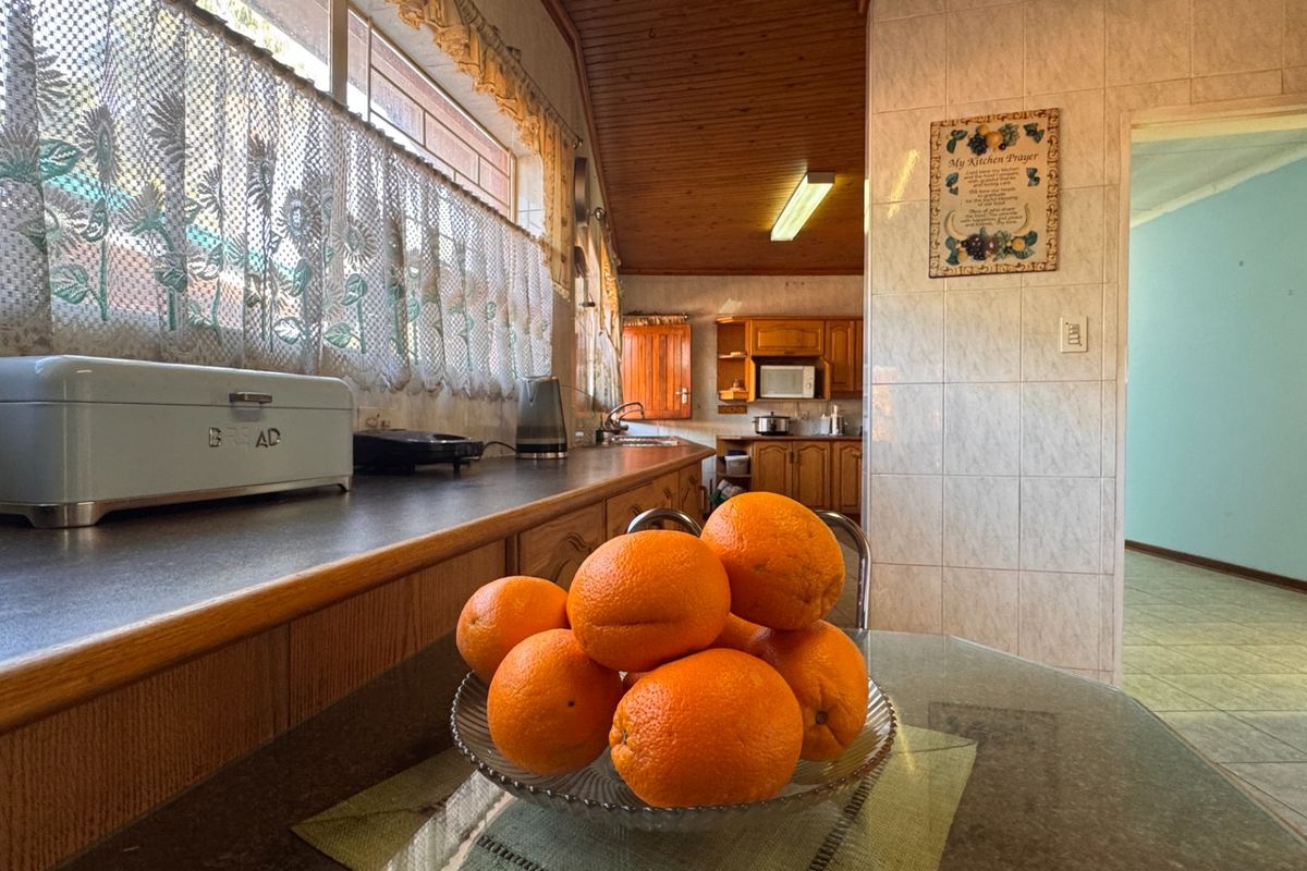 A dated kitchen featuring timber cabinetry, tiled walls, and a timber-paneled ceiling, offering a functional layout with ample counter space.