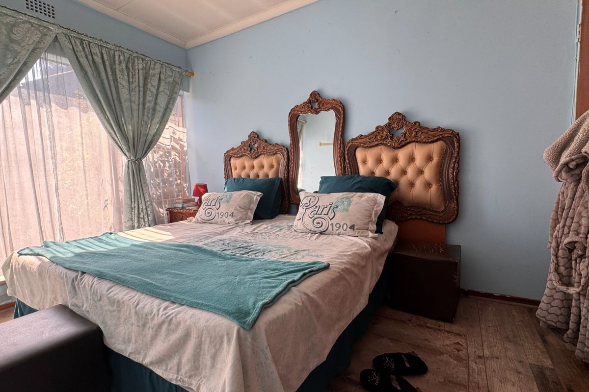 A bedroom featuring a large window with curtains and wood-look flooring.