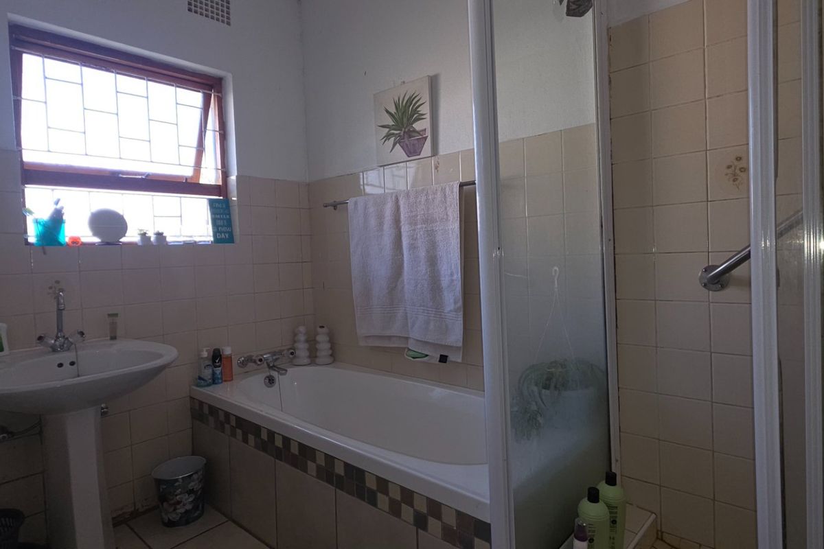 A functional bathroom featuring a pedestal basin, a built-in bathtub, and a separate shower enclosure with tiled finishes.