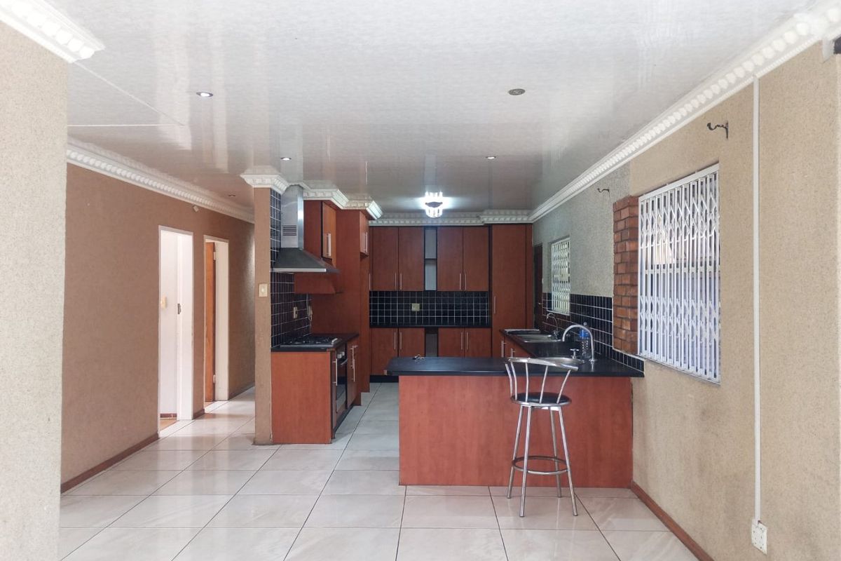 Spacious kitchen featuring wooden cabinetry, a central island, tiled flooring, and built-in appliances, offering a functional layout with potential for modern updates.