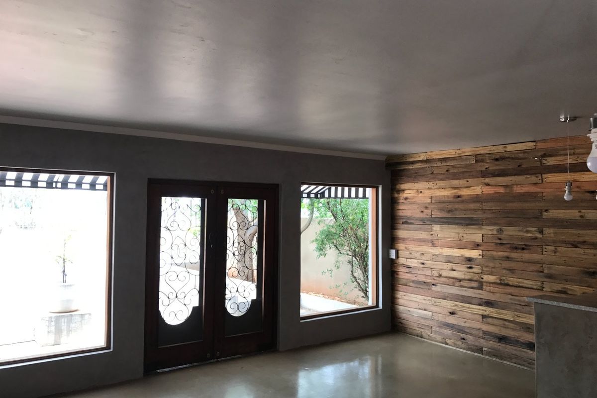 Spacious interior area featuring polished concrete flooring, a rustic timber feature wall, and large windows providing ample natural light.