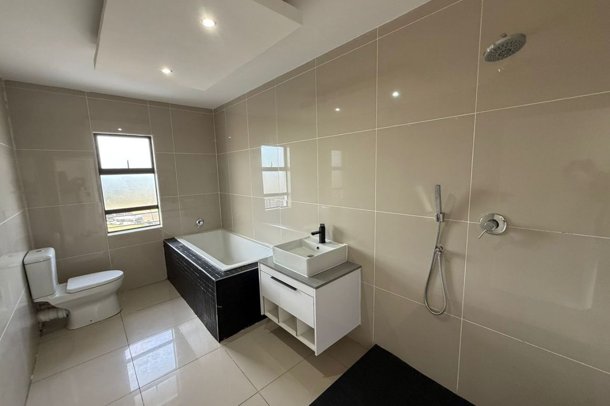 Modern bathroom featuring a built-in bathtub, wall-mounted vanity with vessel sink, and a separate shower area with contemporary tiling and fixtures.