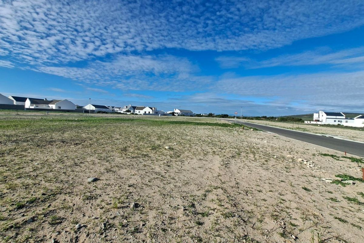 A vacant residential plot of land situated in a developed estate, featuring direct access to a paved road and established street lighting.