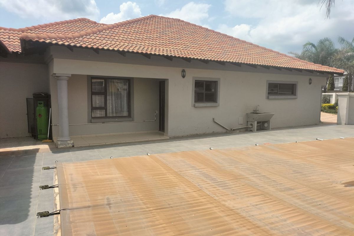 Rear exterior view of the house featuring a covered patio, tiled pool deck with a pool cover, and a utility sink area.