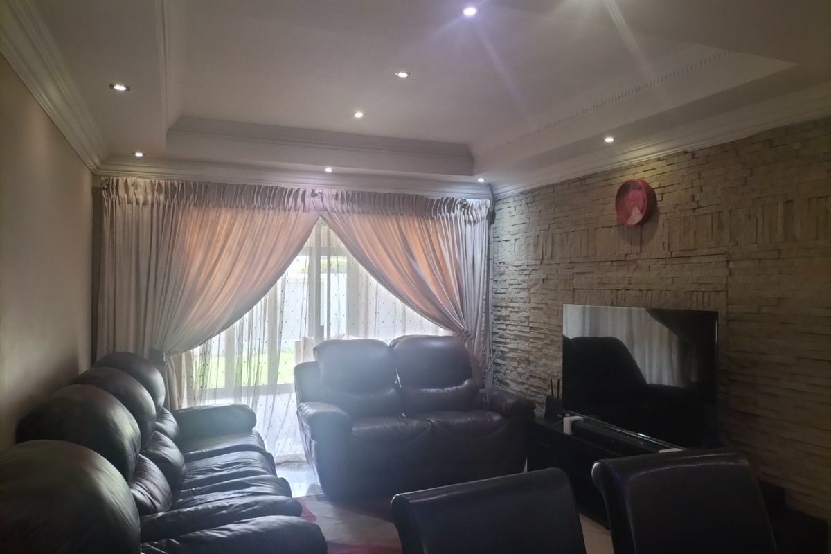 A comfortable living room featuring a textured stone accent wall, recessed ceiling lighting, and large sliding glass doors providing natural light.