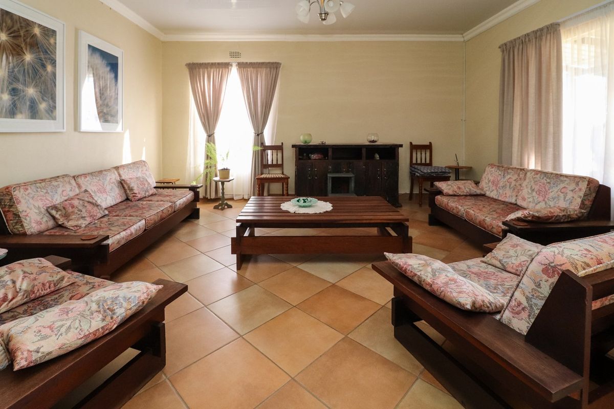 A spacious living room featuring neutral wall tones, tiled flooring, and classic ceiling cornicing, offering a comfortable and functional layout.