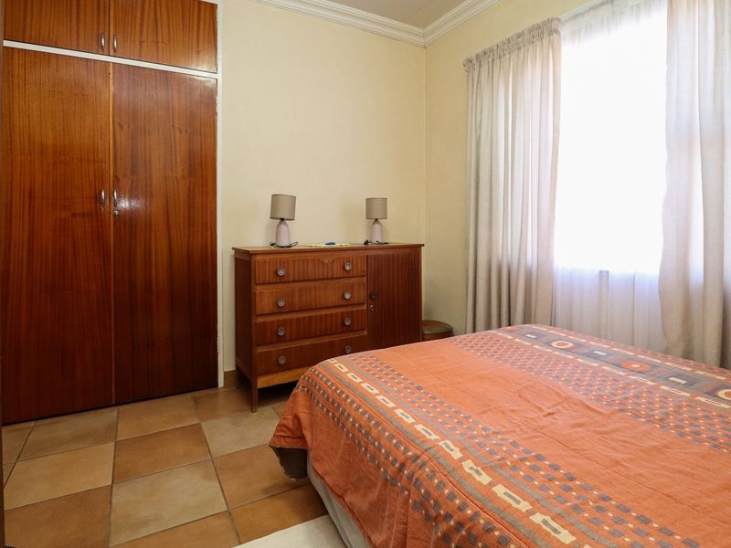 A bedroom featuring tiled flooring, a built-in wooden wardrobe, and decorative cornice detailing.