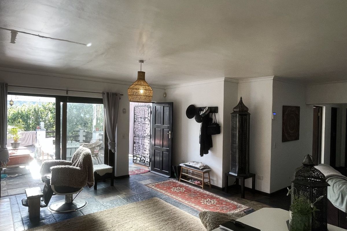 Spacious living area featuring slate tile flooring, natural light from sliding glass doors, and direct access to an outdoor patio space.