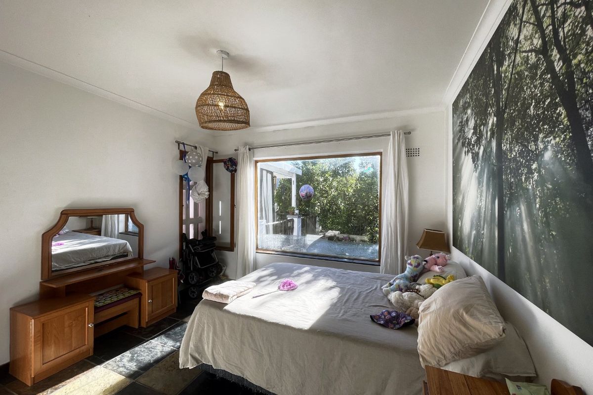 A bedroom featuring large picture windows providing natural light, stone tile flooring, and classic cove cornicing.