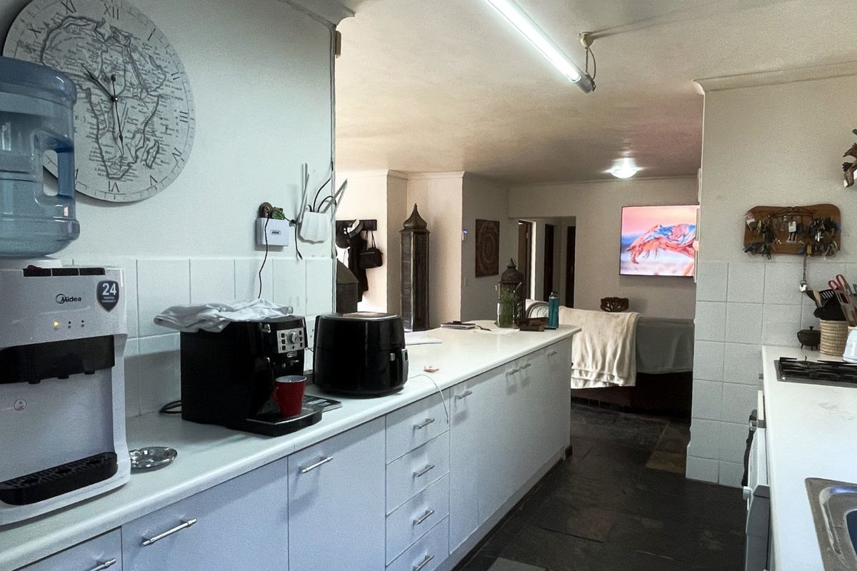 A functional kitchen featuring white cabinetry, laminate countertops, and a gas hob, with an open-plan layout flowing into the adjacent living area.
