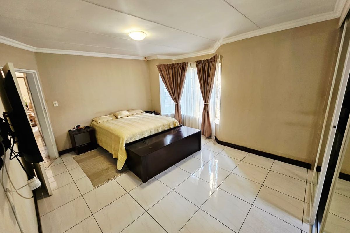 Spacious bedroom featuring large format floor tiles, built-in cupboards, and a coved ceiling, offering a neutral canvas for personalization.
