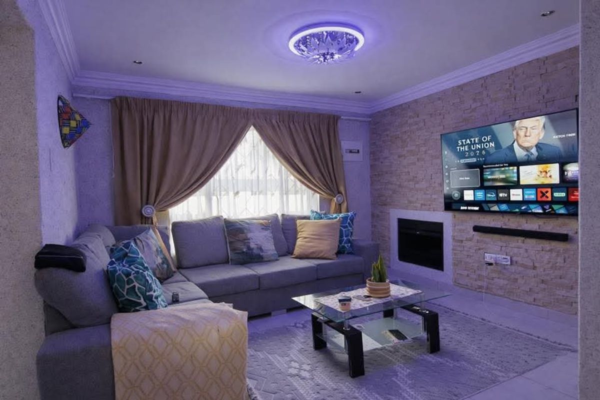 A cozy living room featuring a stone accent wall with a built-in fireplace, recessed ceiling lighting, and decorative crown molding.