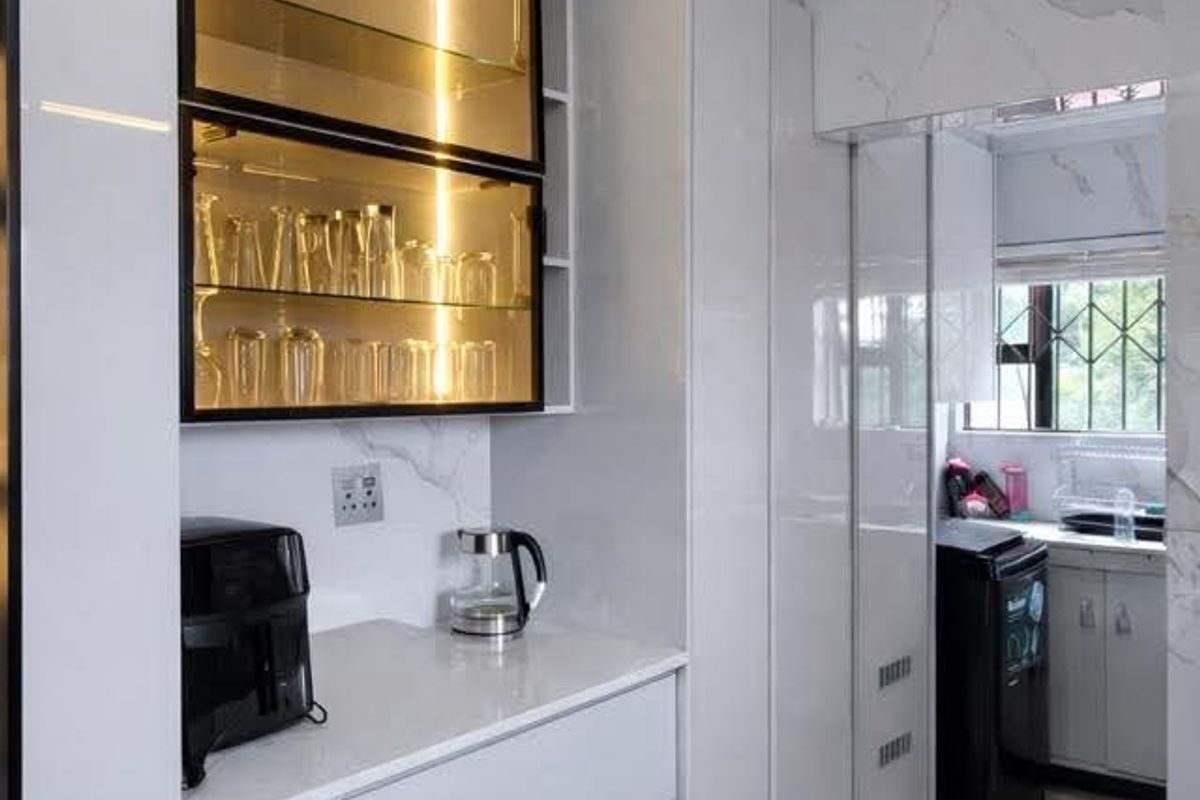 Modern kitchen featuring sleek white cabinetry, quartz countertops, and elegant glass-front display shelving with integrated lighting, leading into a functional scullery area.