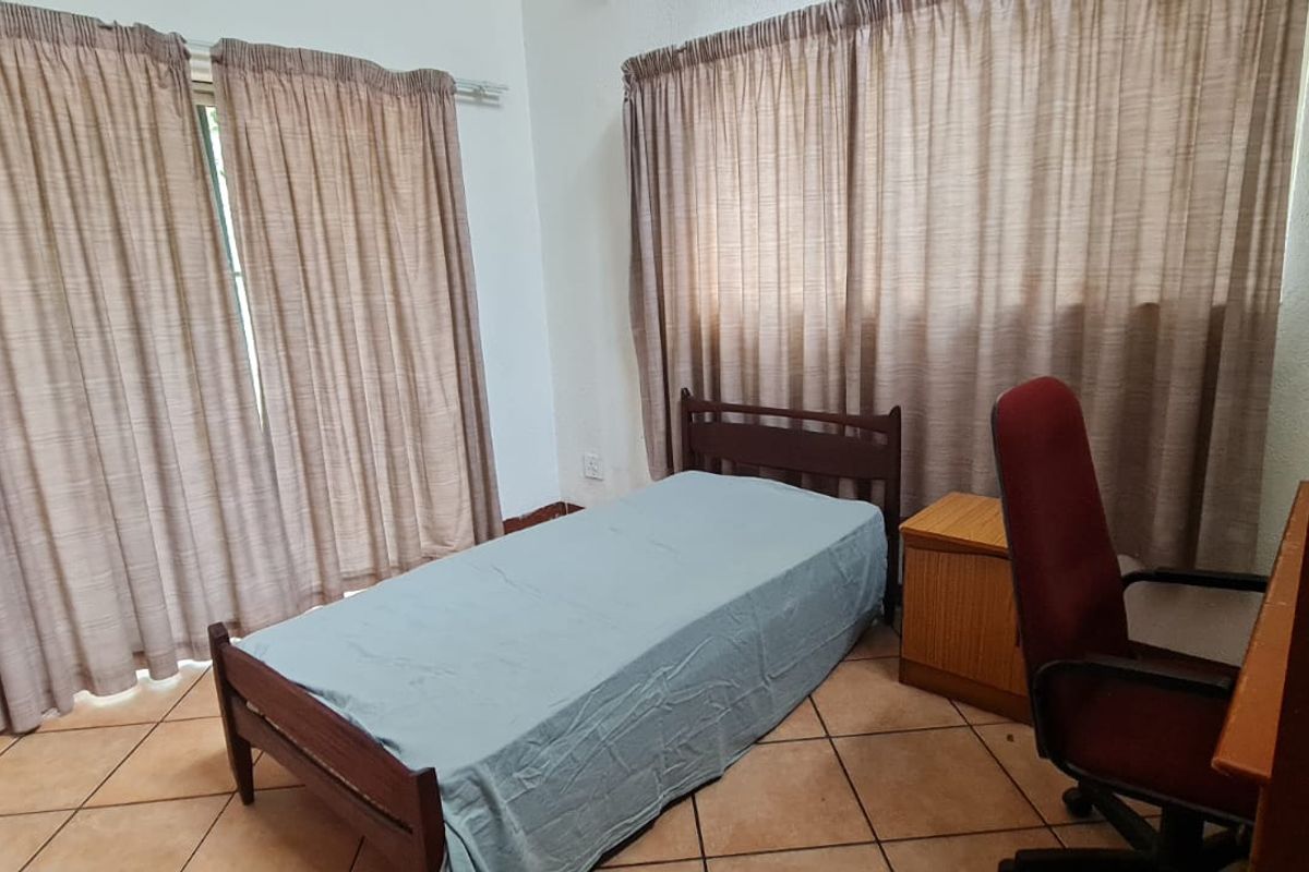 A functional bedroom featuring tiled flooring and dual window treatments, providing a neutral base for potential interior updates.