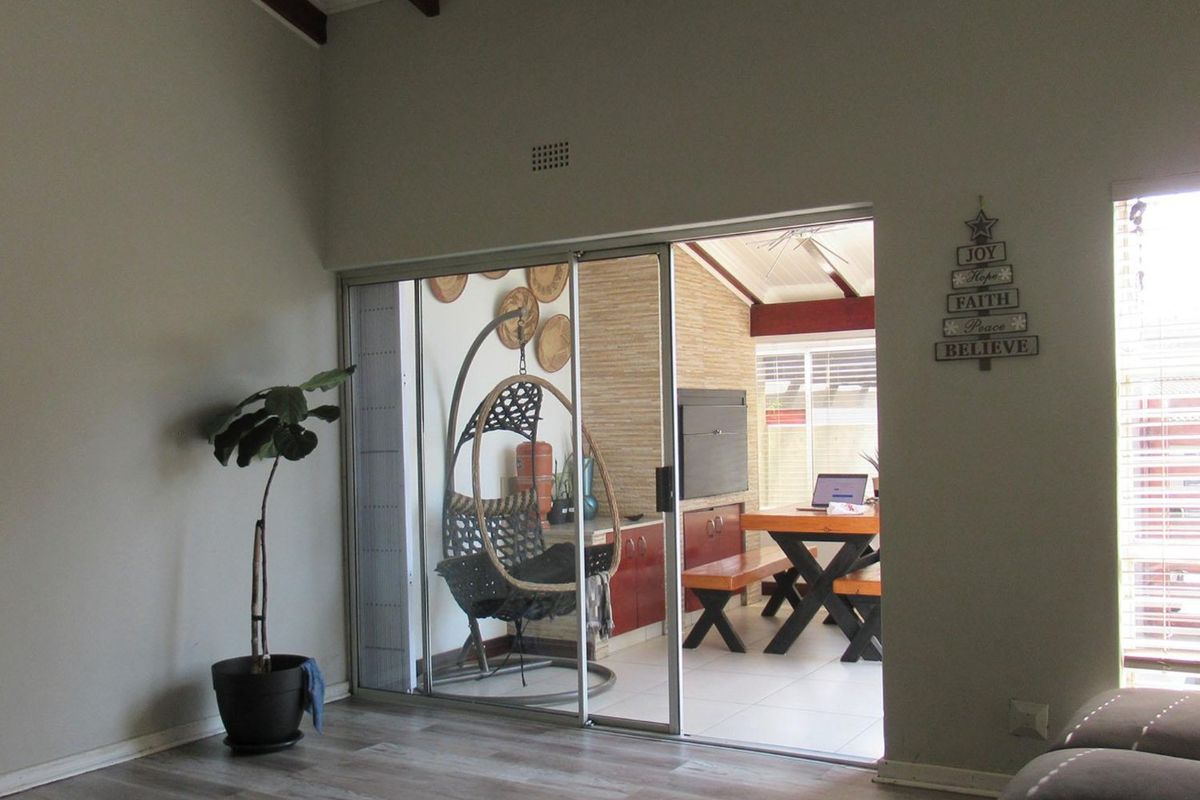 Living room featuring wood-look flooring and a large sliding glass door providing access to an enclosed patio area with exposed timber beams.