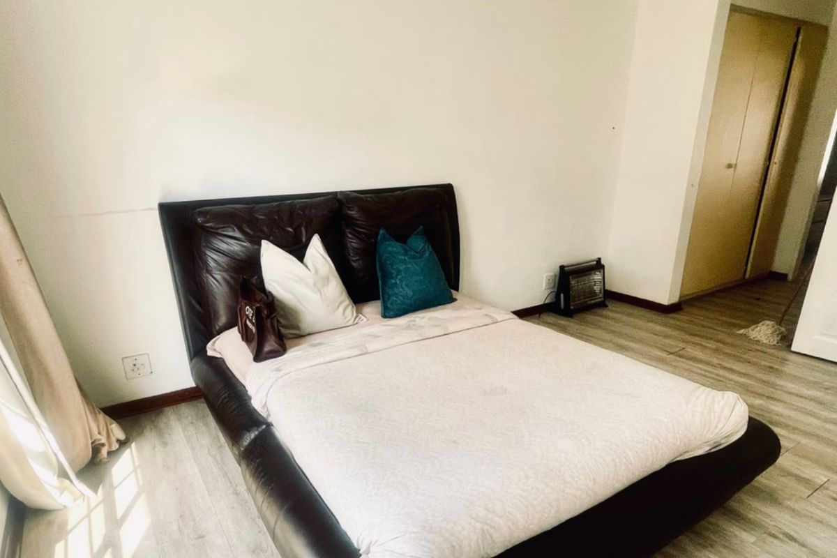 A bedroom featuring laminate flooring and built-in cupboards, offering a functional space with natural light.