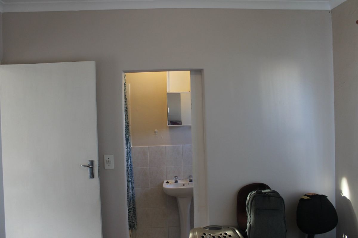 A functional bathroom featuring a pedestal basin, tiled splashback, and a wall-mounted medicine cabinet, accessible via a standard interior doorway.