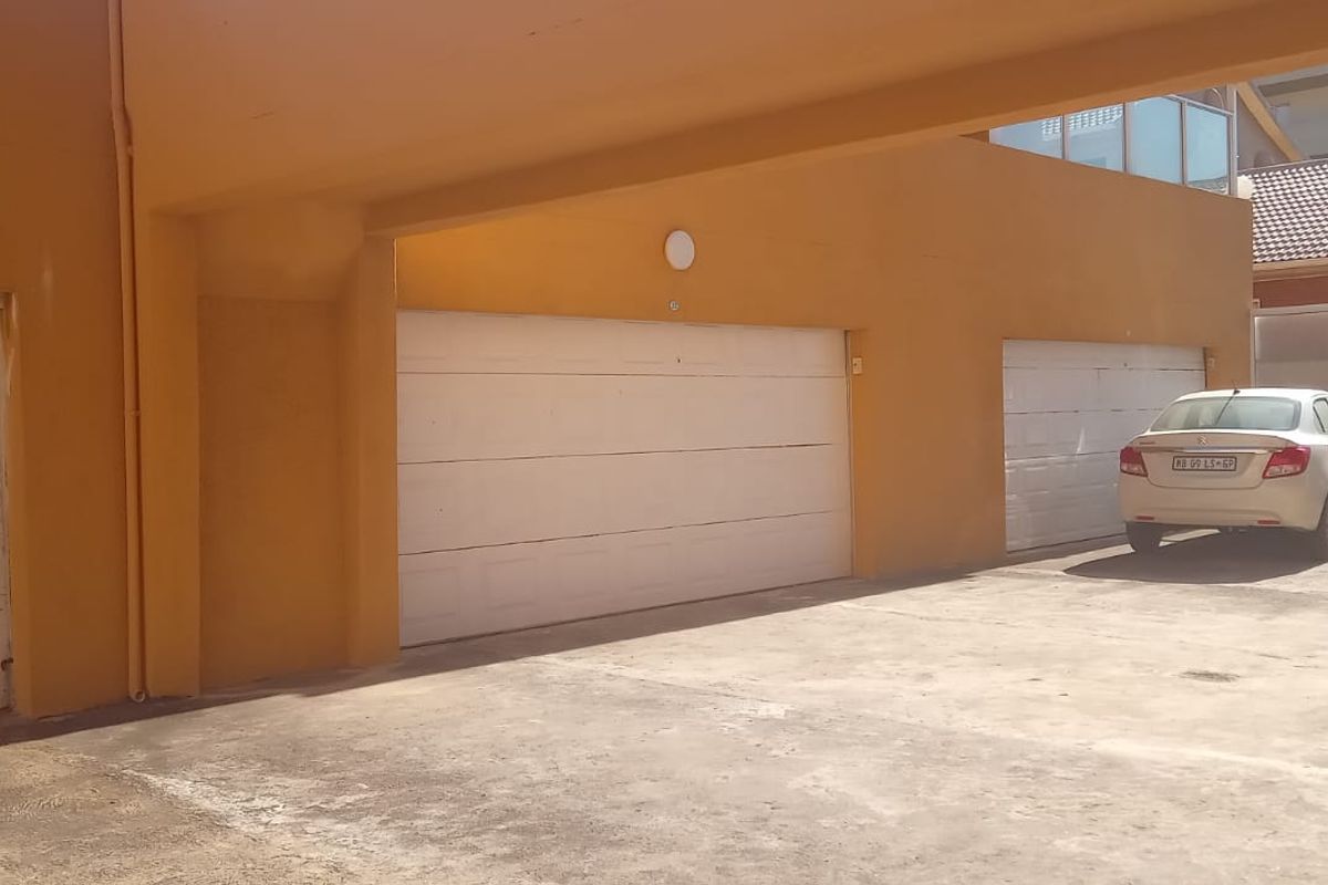 Exterior view of a multi-unit garage complex with concrete driveway and covered parking area.