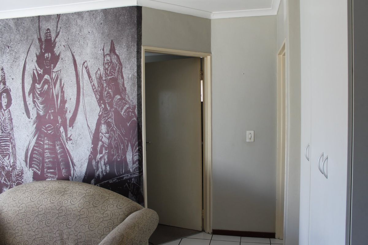 A bedroom interior featuring built-in cupboards and a decorative feature wall.