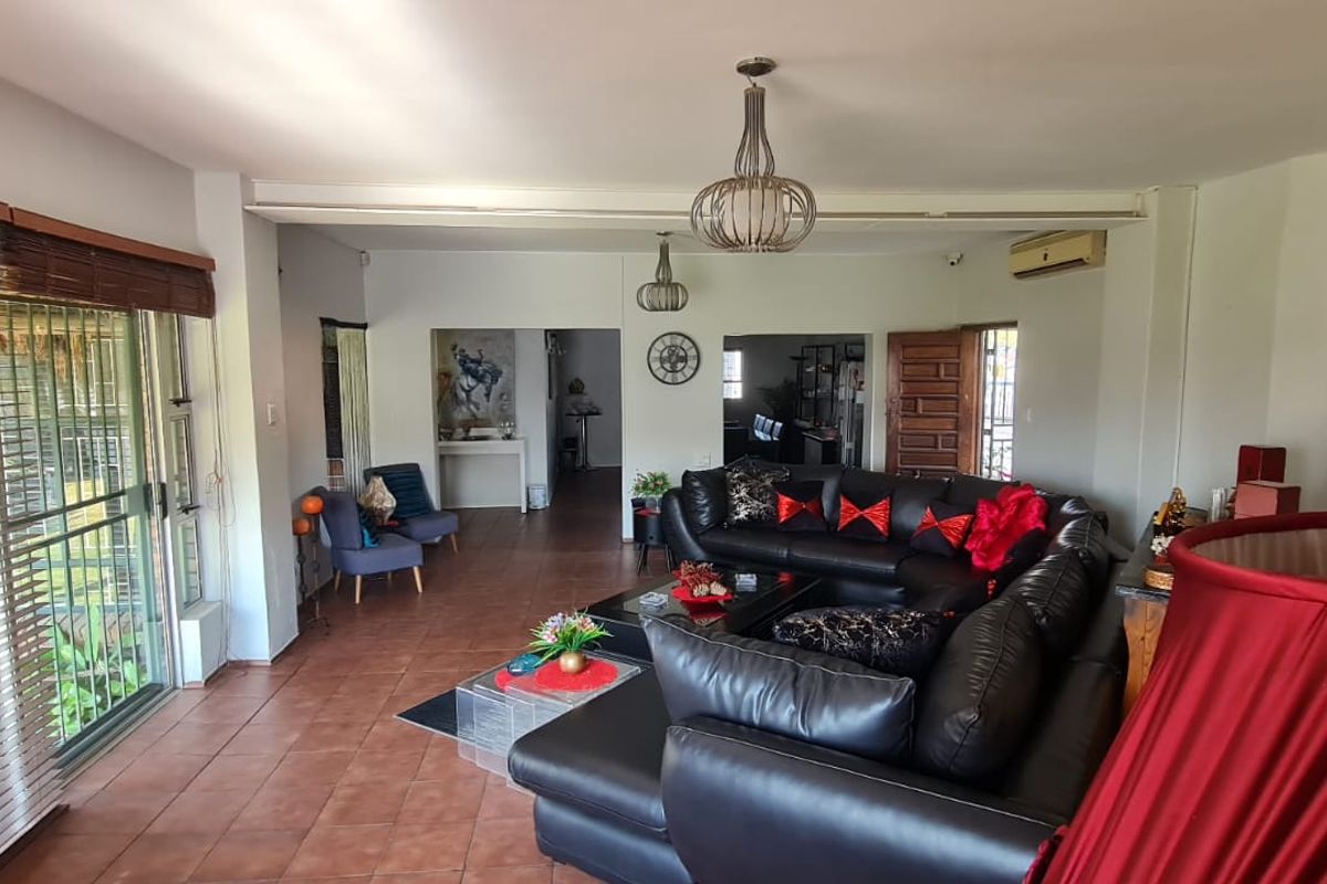 Spacious living area featuring terracotta floor tiles, large sliding glass doors for natural light, and a wall-mounted split-system air conditioner.