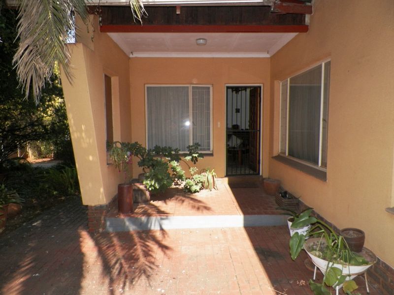 A covered patio area featuring brick paving and a security gate entrance, providing a functional outdoor space for the home.