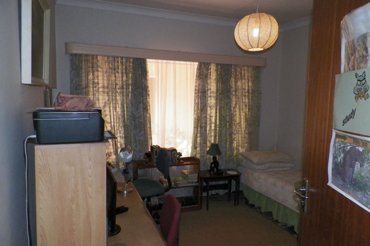 A functional bedroom featuring carpet flooring, cove cornicing, and a fitted curtain pelmet, offering a neutral base for potential updates.