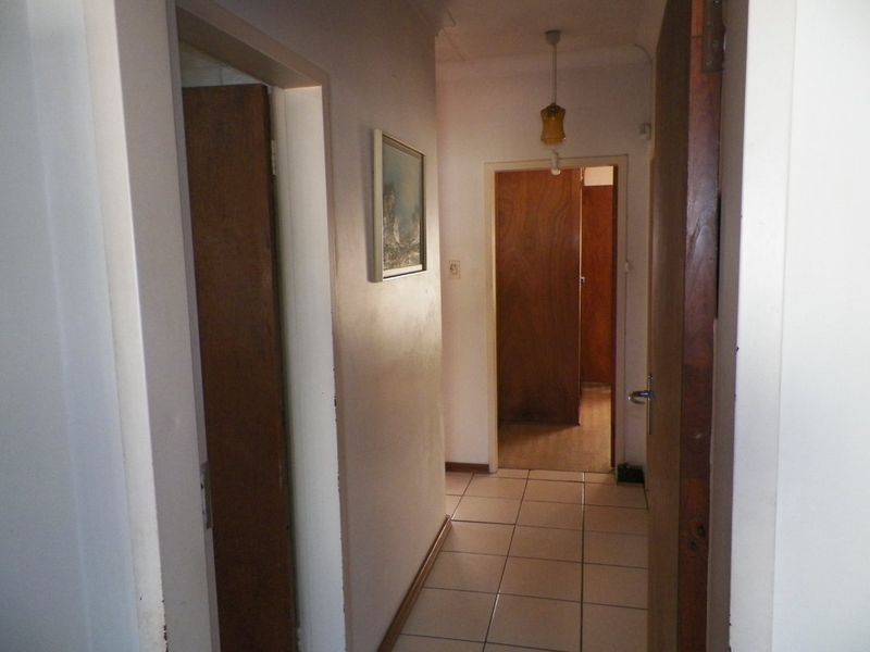 A functional hallway featuring tiled flooring and solid wood doors, providing access to multiple rooms within the home.