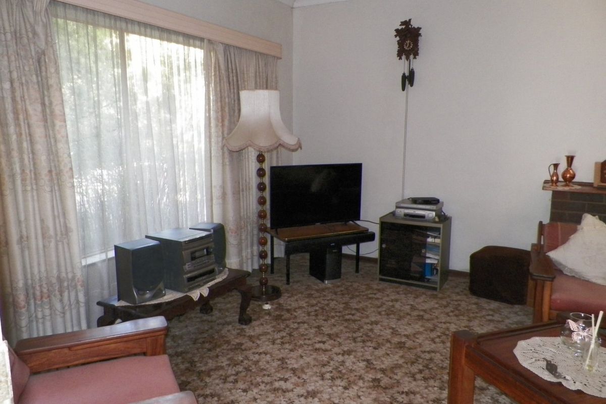 A living room featuring patterned carpet flooring and coving, offering a dated interior space ready for modernization.
