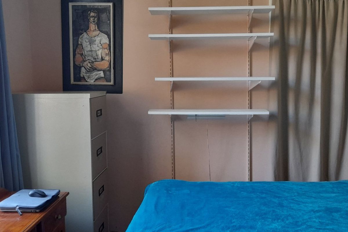 A bedroom featuring a leaded glass window and a wall-mounted shelving unit, providing functional storage space.