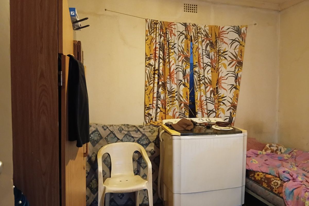 A bedroom space featuring basic wall finishes and a ventilation grille, currently requiring maintenance and cosmetic updates to improve its overall condition.