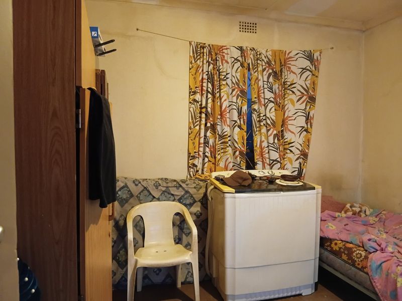 A bedroom space featuring basic wall finishes and a ventilation grille, currently requiring maintenance and cosmetic updates to improve its overall condition.