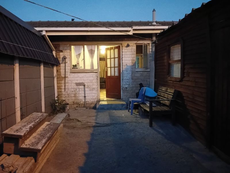 Rear exterior view of the property featuring a brick facade, timber door, and concrete paved courtyard area.