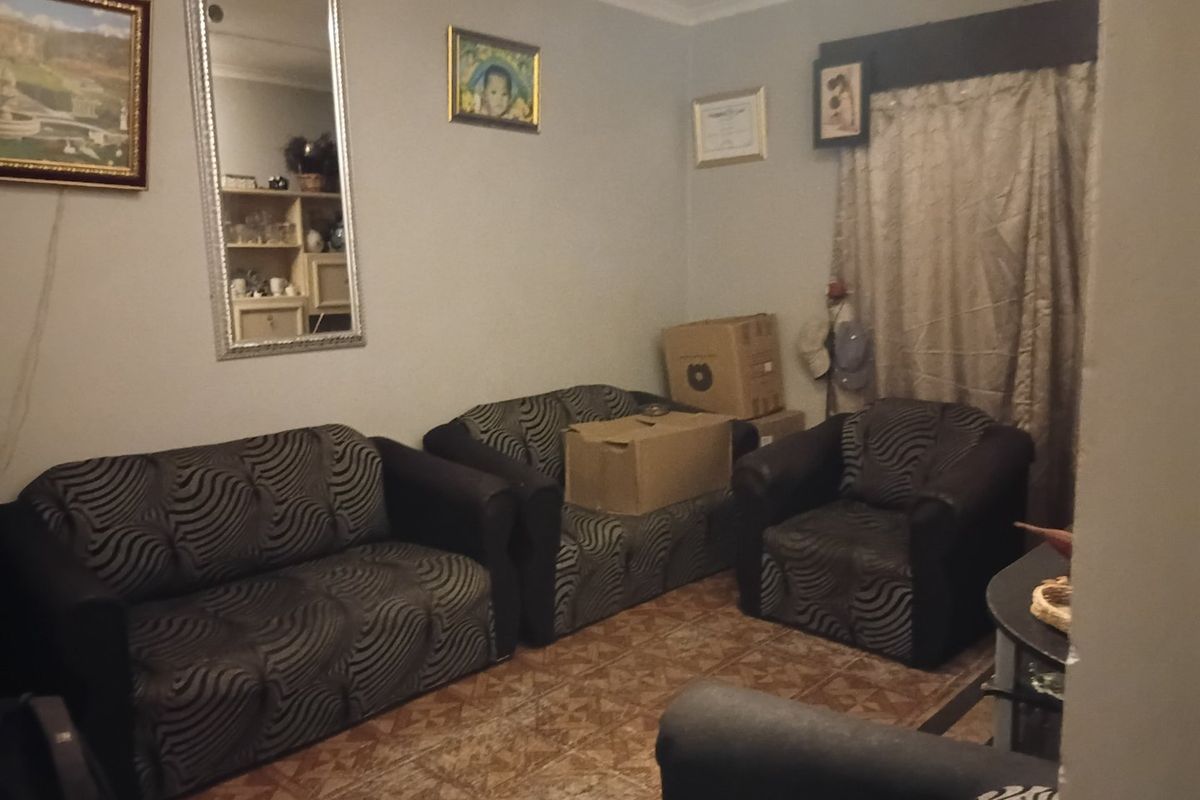 A living room area featuring tiled flooring and decorative cornicing, providing a functional space for relaxation.