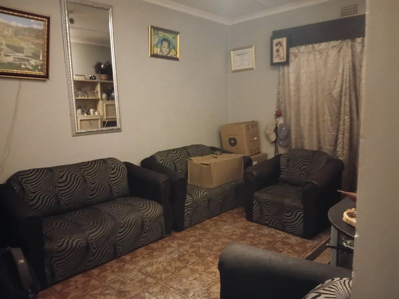 A living room area featuring tiled flooring and decorative cornicing, providing a functional space for relaxation.