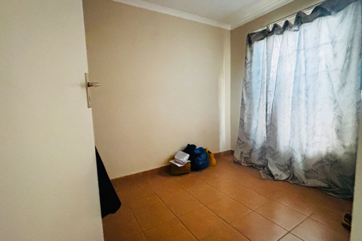 A simple, empty bedroom featuring tiled flooring and coved ceiling cornices, offering a blank canvas for personalization.