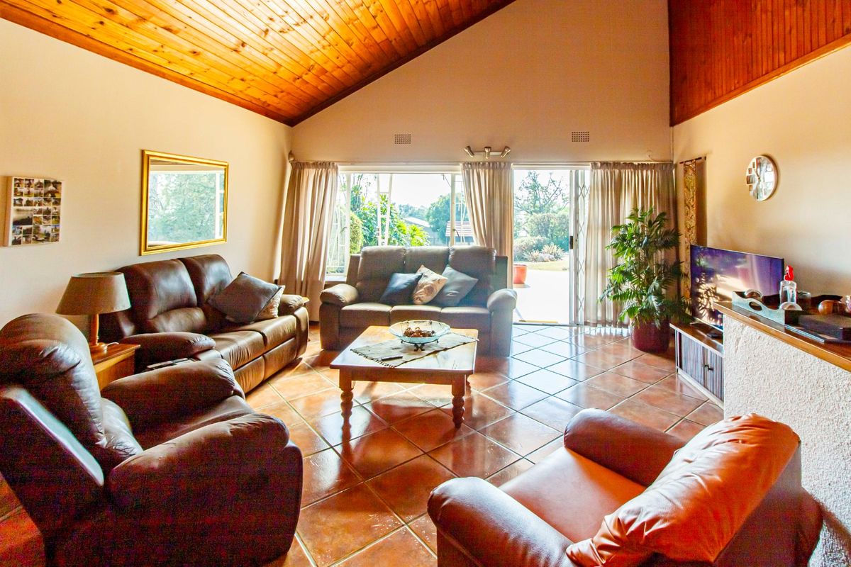 Spacious living room featuring a high vaulted timber ceiling, terracotta tiled flooring, and direct access to the outdoor area through sliding glass doors.