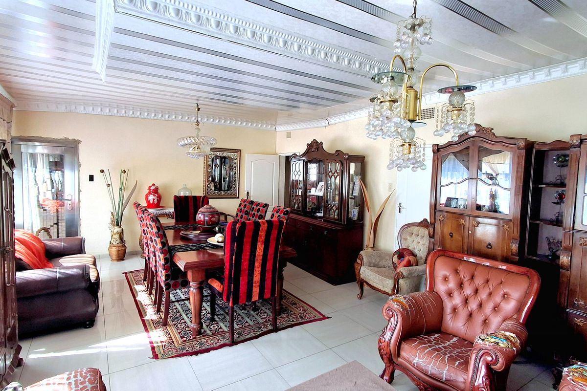 Spacious dining room featuring tiled flooring, ornate ceiling molding, and a classic crystal chandelier, offering a traditional aesthetic with potential for modern updates.