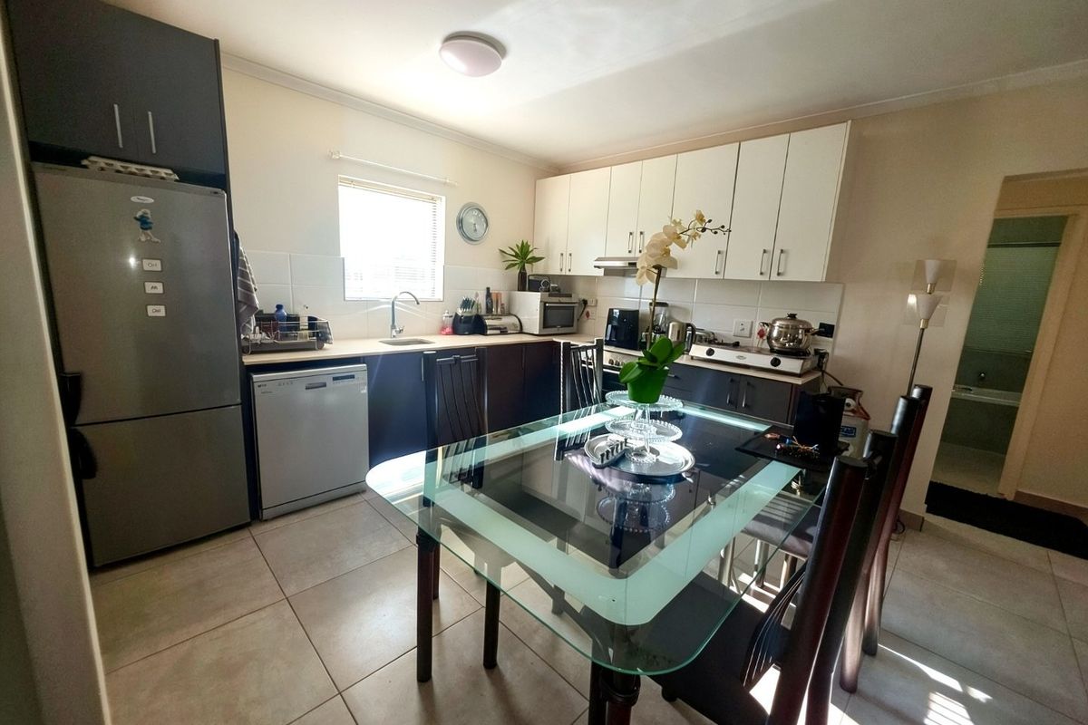 A functional kitchen featuring two-tone cabinetry, laminate countertops, tiled flooring, and an integrated extractor fan, providing a practical workspace for daily cooking.