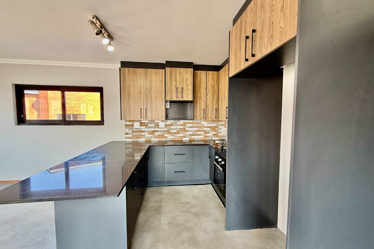 Modern kitchen featuring two-tone cabinetry, granite countertops, a breakfast bar, and built-in oven, offering a clean and functional workspace.
