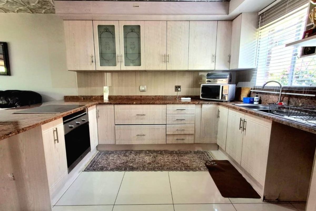 A functional kitchen featuring light-toned cabinetry, granite countertops, built-in oven, and tiled flooring, offering a practical layout for daily meal preparation.