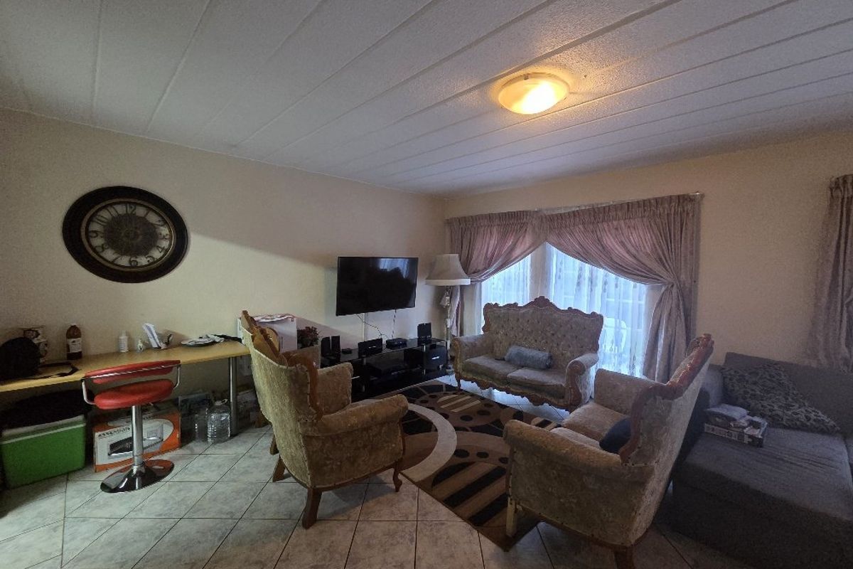 A living room featuring tiled flooring and a panelled ceiling, providing a functional space for relaxation and entertainment.
