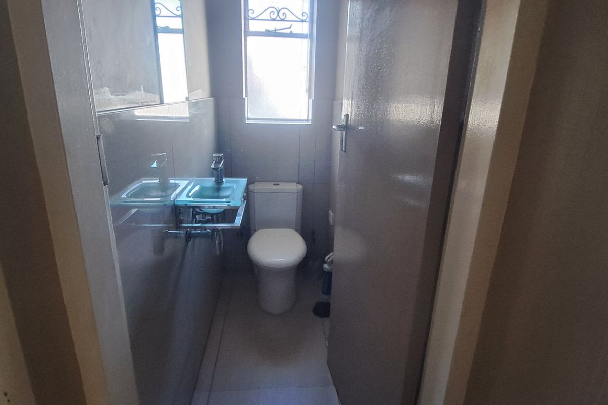 A compact bathroom featuring a modern glass vanity basin, a standard toilet, and tiled finishes throughout.