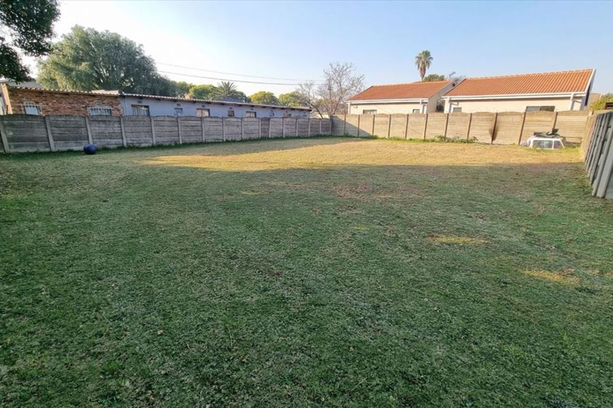 A spacious, level backyard area enclosed by precast concrete boundary walls, offering a blank canvas for landscaping or outdoor development.