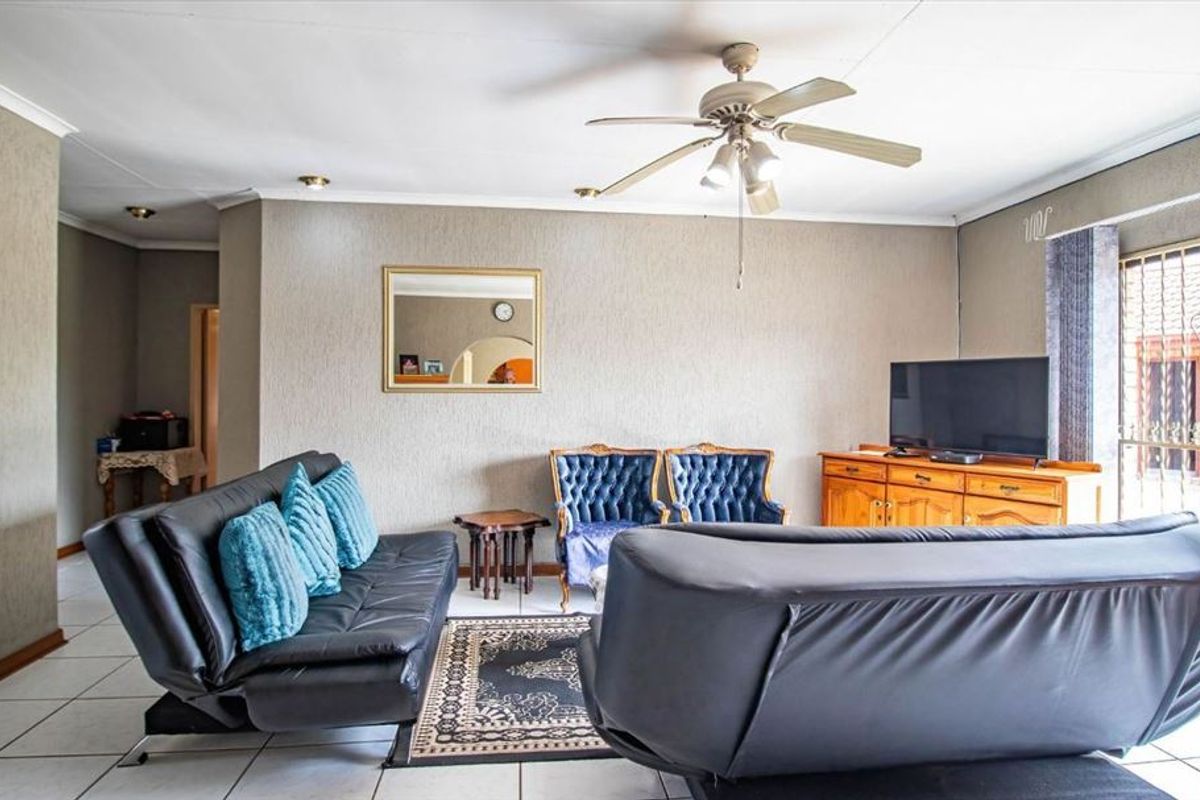 A spacious living room featuring tiled flooring, a ceiling fan, and recessed lighting, providing a comfortable and functional area for relaxation.