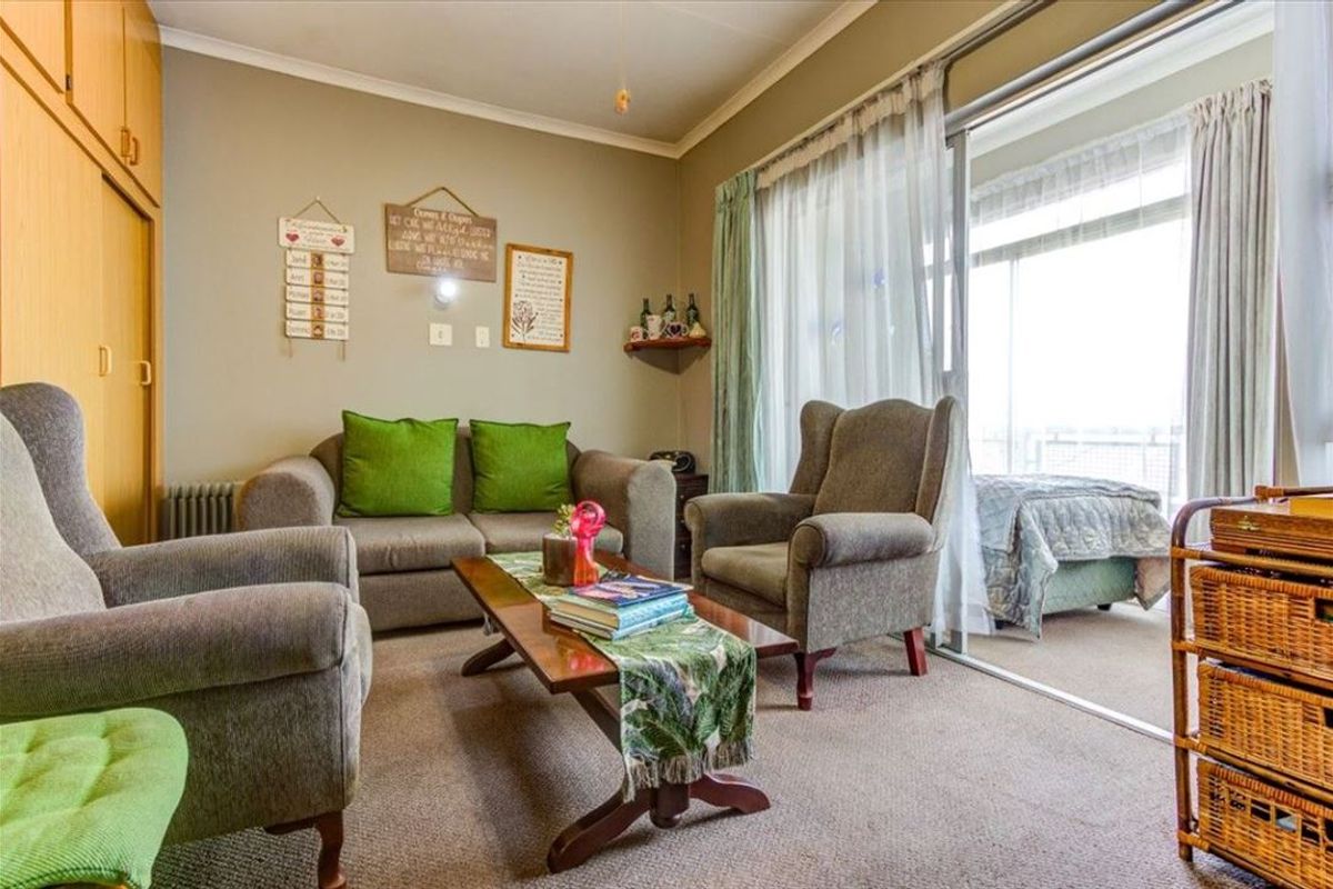 A living room featuring built-in cupboards, a radiator, and a large sliding glass door providing access to an adjacent space.