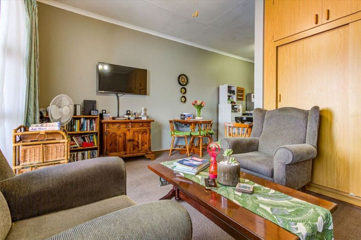 A living room area featuring built-in wooden cupboards and carpeted flooring, providing a functional and comfortable space within the townhouse.